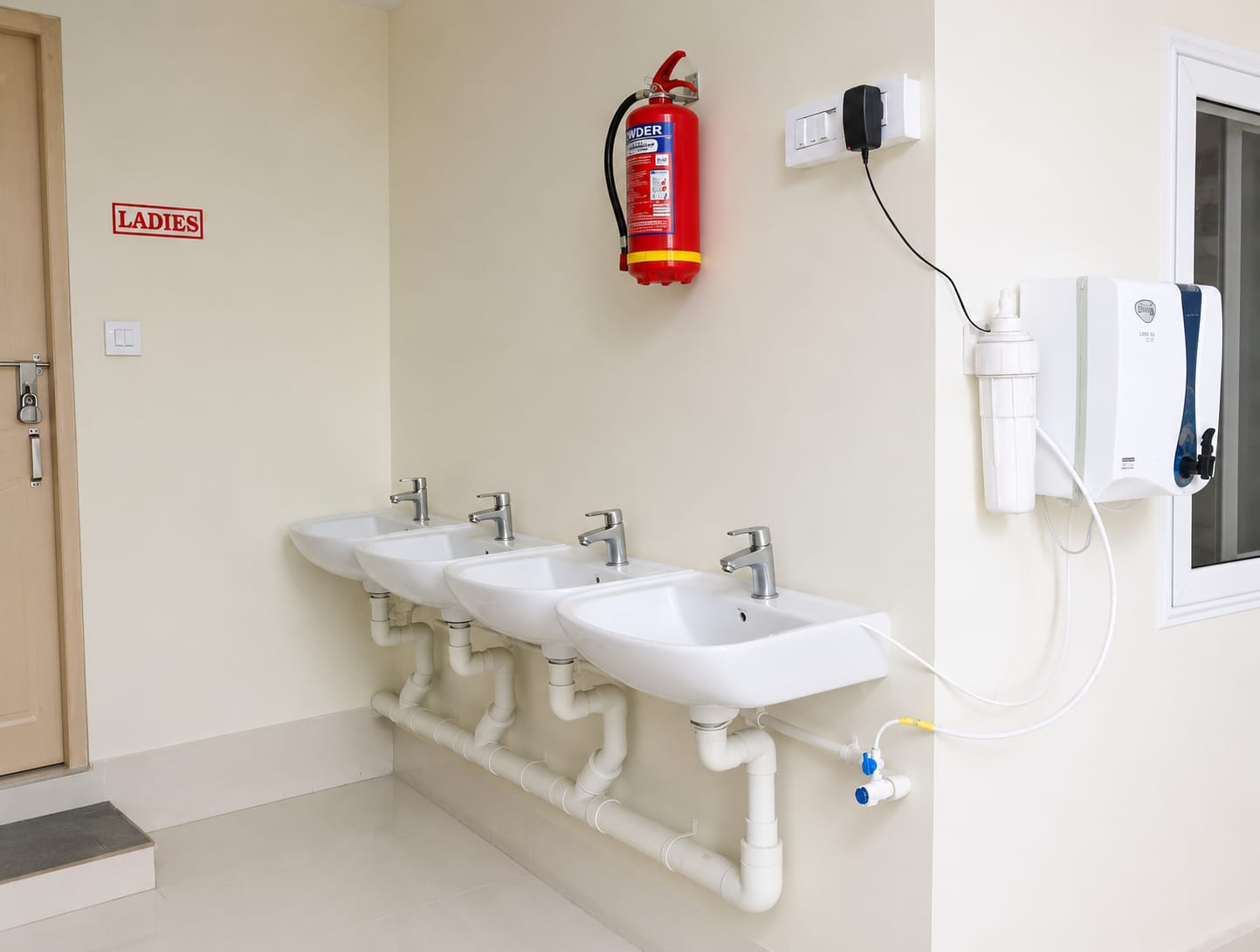 Clean ladies washroom area with a row of wash basins and purified water station